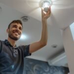 man changing a light bulb while doing household tasks