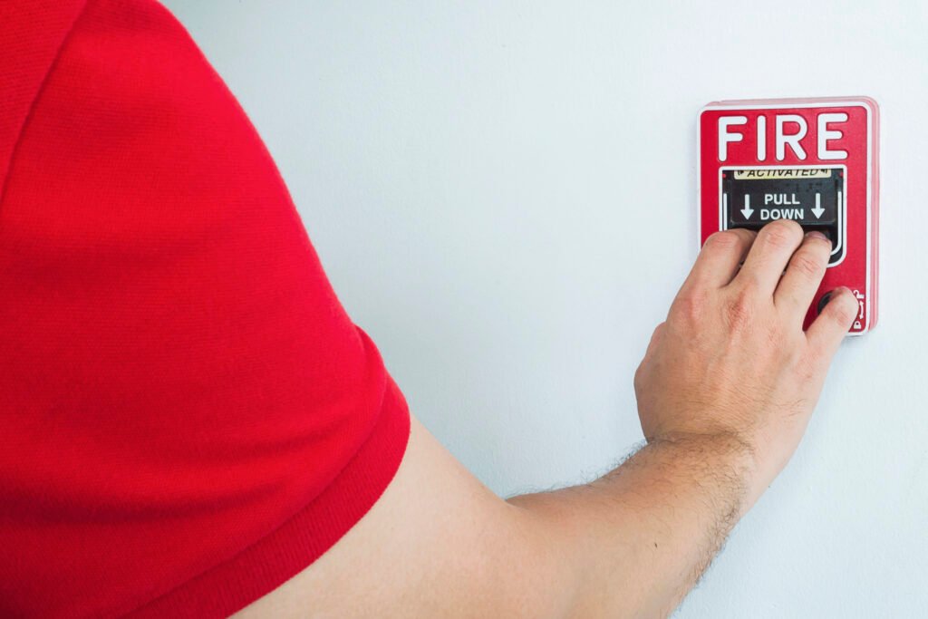 man reaching to push a fire alarm hand station